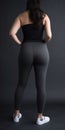 Model slim fit girl in gray yoga pants. standing with back to camera. Curvy body