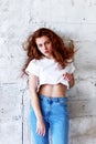 Model tests. Beautiful redhead girl with curly hair.Natural color. Stands with long hair blowing against the light brick Royalty Free Stock Photo