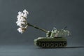 Model toy of battle tank firing flowers from the barrel. Peace and no war concept. Military pancer on the gray background Royalty Free Stock Photo