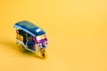 Model Toy tuk tuk isolated on yellow background. Thai traditional taxi in Bangkok Thailand. Souvenir Royalty Free Stock Photo