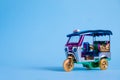 Model Toy tuk tuk isolated on blue background. Thai traditional taxi in Bangkok Thailand. Souvenir Royalty Free Stock Photo