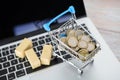 A model of a trolley full of euro coins and cargo on a laptop