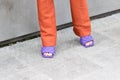 Model wearing a pair of orange trousers and a pair of purple slippers