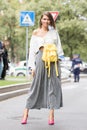 Model wearing a pair of silver pants, a shirt with a yellow backpack attached and a pair of pink heeled shoes Royalty Free Stock Photo