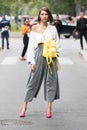 Model wearing a pair of silver pants, a shirt with a yellow backpack attached and a pair of pink heeled shoes Royalty Free Stock Photo