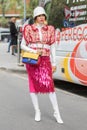 Model wearing a pair of white boots, a pink skirt, a white hat and a multicolored Gucci handbag