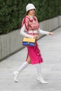 Model wearing a pair of white boots, a pink skirt, a white hat and a multicolored Gucci handbag