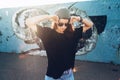 Model wearing plain tshirt and sunglasses posing over street wall