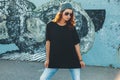 Model wearing plain tshirt and sunglasses posing over street wall