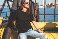 Model wearing plain tshirt and sunglasses posing over street wall