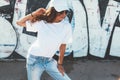 Model wearing plain tshirt and sunglasses posing over street wall