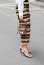 Model wears a pair of golden and black stripes trousers as well as an original semi-transparent handbag