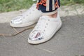 Model wears a pair of white snekers with a shiny silver tip