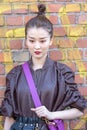 Model wears a perforated brown jacket and a purple shoulder bag