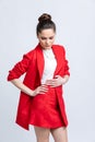 Model in white blouse, red skirt and jacket and white sandals with silver chain and pendant on neck, on white background.