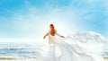 Model in White Dress Flying on Wind. Happy Woman Enjoying Sun looking away at Blue Sky. Carefree Girl dreaming at Sea Beach Resort