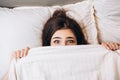 model woman hiding under the blanket. Young woman is very scared. Woman with big open eyes in bed Royalty Free Stock Photo