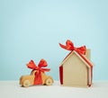 Model of a wooden house and car toy tied with a red silk ribbon on a blue background, concept of real estate purchase, mortgage Royalty Free Stock Photo