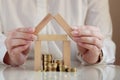 Model of a wooden house and a pile of money in coins, hands are building a house, mortgage and bank interest concept, deposit insu Royalty Free Stock Photo