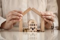 Model of a wooden house and a pile of money in coins, hands are building a house, mortgage and bank interest concept, deposit insu Royalty Free Stock Photo