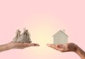 A model wooden house and a sack of money in the hands of two people. Concept of saving money to buy a house