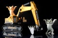 Model of a yellow caterpillar excavator with two funny toy kittens on black background. Mining concept. Concept of compliance with