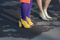 Models wears a pair of yellow shoes with heels and purple socks and golden ankle boots