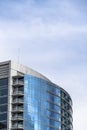 Moden building with glass walls and balconies viewed against cloudy blue sky