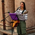 Female musician playing acoustic guitar and singing outdoor in Italy.