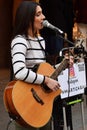 Female musician playing acoustic guitar and singing outdoor. Italy