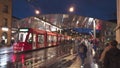 Moder architecture glass roof tram and bus stop in Bern city center, many people walking accross the street.