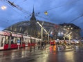 Moder architecture glass roof tram and bus stop in Bern city center, many people walking accross the street.