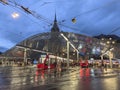 Moder architecture glass roof tram and bus stop in Bern city center, many people walking accross the street.