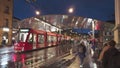 Moder architecture glass roof tram and bus stop in Bern city center, many people walking accross the street.