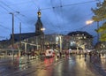 Moder architecture glass roof tram and bus stop in Bern city center, many people walking accross the street.