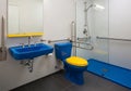 Modern, accessible bathroom with bright blue and yellow color scheme. Features include a blue sink Royalty Free Stock Photo