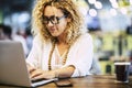 Modern adult caucasian woman working on a laptop computer at her worlplace desktop - people at work with technology concept - Royalty Free Stock Photo