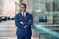 Modern African American CEO portrait standing confidently, with arms crossed, at swanky luxurious office building Royalty Free Stock Photo