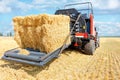 A modern agricultural machine collects straw into large bales after the end of the wheat harvest