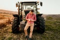 Modern agriculture with technology and machinery concept. Portrait of smiling farmer using smartphone and tractor at harvesting