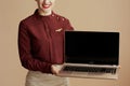 Modern air hostess woman on beige showing laptop blank screen Royalty Free Stock Photo