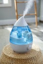 Modern air humidifier on wicker pouf indoors