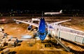 Modern airplane parked at the gate for boarding of passengers at an airport at night with motion of the ground vehicles. Vietnam