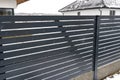 Modern anthracite panel fencing with a visible connector of the fence foundations, it rains in winter, in the background the roofs Royalty Free Stock Photo