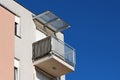 Modern apartment building corner balcony surrounded with grey metal safety fence and closed window blinds covered with transparent