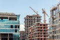 Modern apartment residential building glass facade wall construction site with many high tower cranes and heavy Royalty Free Stock Photo