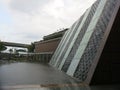 Modern Architects Singapore. Waterfall running down the wall of a building. Rain drops fall to the ground and form puddles. The co