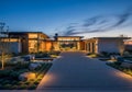 Modern architectural home with expansive driveway, flanked by landscaped gardens and illuminated Royalty Free Stock Photo