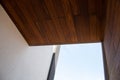 Modern architecture detail of wooden facade cladding, white wall and sky background