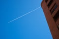 Modern architecture and jet contrail overhead against clear blue sky Royalty Free Stock Photo